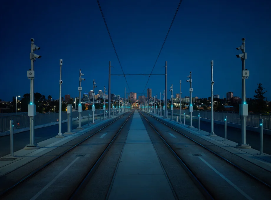 Light rail corridor at dusk with pole-mounted sensors monitoring the right-of-way