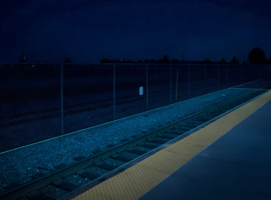Security camera view of a rail track bed and platform edge with a monitored detection zone